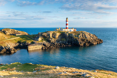 Lighthouse by sea against sky