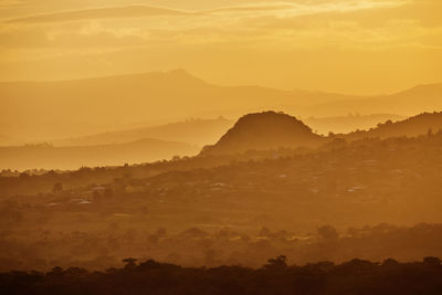 Scenic view of silhouette mountains against orange sky