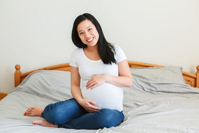 Smiling young woman sitting on bed