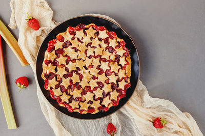 Strawberry and rhubarb pie decorated with stars on grey table, top view
