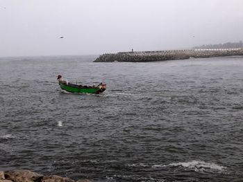 People in sea against clear sky