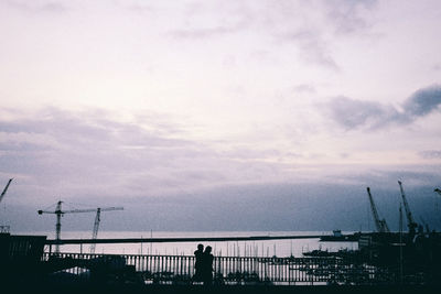 Silhouette man by sea against sky during sunset