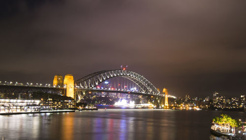 Illuminated bridge over bay in city at night