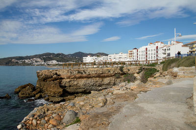 Scenic view of sea by buildings against sky