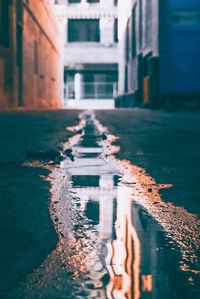 Wet street amidst buildings in city