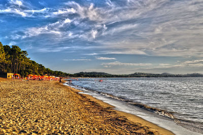 Scenic view of beach against cloudy sky