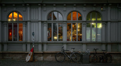 Bicycle parked against illuminated building in city