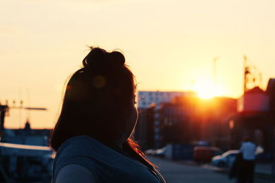 Rear view of woman against sky during sunset