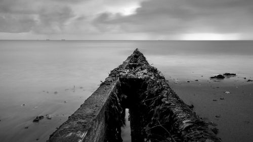 Wooden posts on pier over sea against sky