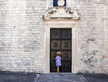 Full length portrait of woman standing against building