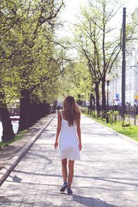 Rear view of woman walking on footpath in city