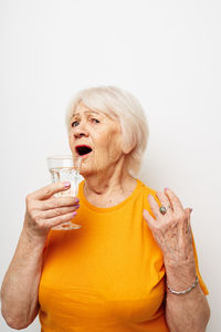 Young woman drinking glass against white background