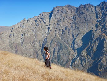 Rear view of woman standing on mountain against sky