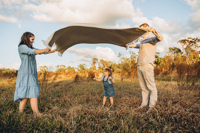 Young couple with cute 2 years old daughter under waving blanket