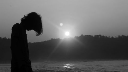 Silhouette man standing by sea against sky during sunset