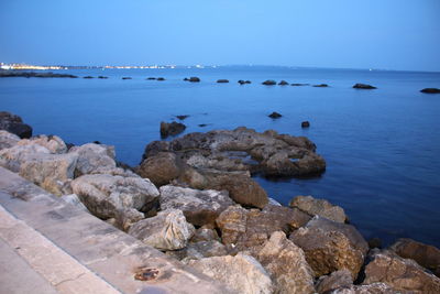 Rocks in sea against blue sky