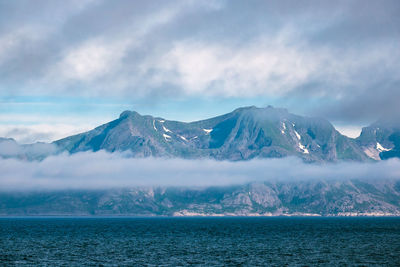 Scenic view of sea and snowcapped mountains against sky