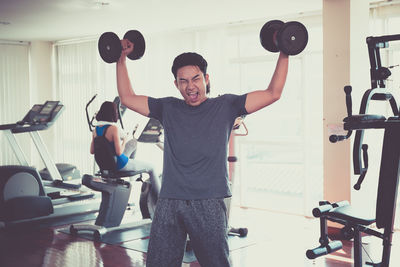 Portrait of man lifting dumbbells in gym