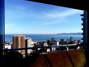 City at waterfront against blue sky