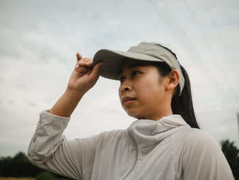 Low angle view of woman wearing cap against sky