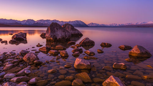 Rocks on sea shore against sky during sunset