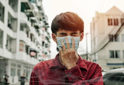 Portrait of young man against buildings in city