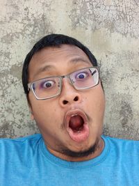 Portrait of man wearing eyeglasses against wall