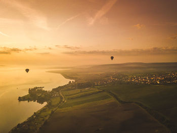 Hot air balloon flying over landscape against sky during sunset