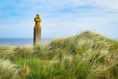 Scenic view of sea against sky with gravestone 