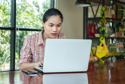 Portrait of young woman using digital tablet at table