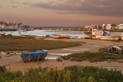 Boats moored on beach against sky during sunset