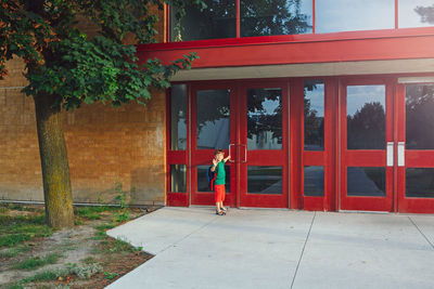 Side view of a red woman against building