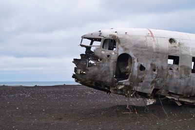 Abandoned airplane on land against sky