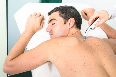 Midsection of shirtless man lying down against gray background