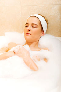 Woman bathing in bathtub at bathroom