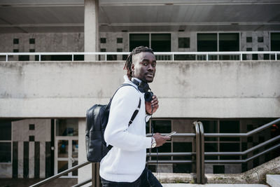 Young man looking away while standing against railing