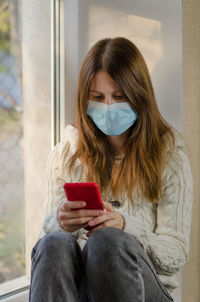 Young woman using mobile phone while sitting on camera