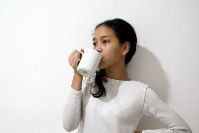 Portrait of boy drinking glass against wall