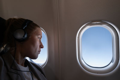 Woman seating in the airplane looking out of the window