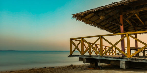 Lifeguard hut on beach against sky during sunset