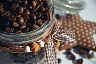 Close-up of roasted coffee beans in decorated jar on table