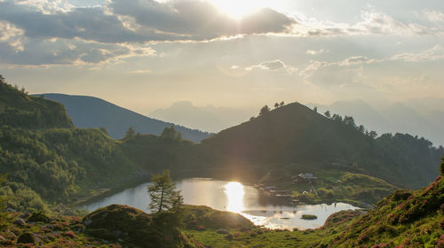 Scenic view of lake and mountains against sky during sunset