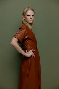 Portrait of young woman standing against wall