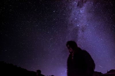 Rear view of man standing against sky at night