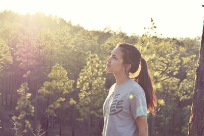 Young woman looking up against trees