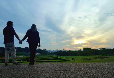 Friends walking on grass against sky