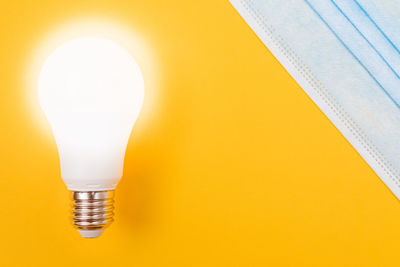 Close-up of illuminated light bulb against wall