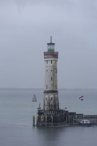 Lighthouse in sea against sky