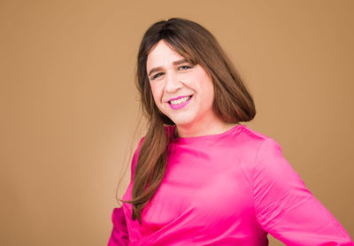 Portrait of young woman standing against yellow background