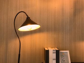 Close-up of illuminated desk lamp against wooden wall